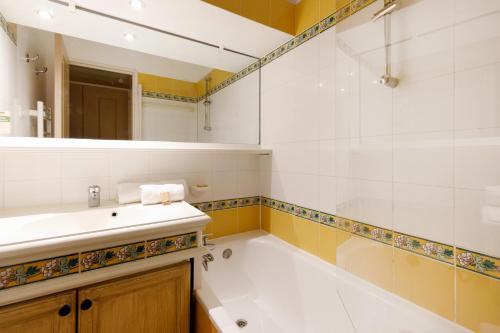 La salle de bains est pourvue d'une baignoire, d'un lavabo et d'un miroir. dans l'établissement Les Pivoines YourHostHelper, à Grimaud