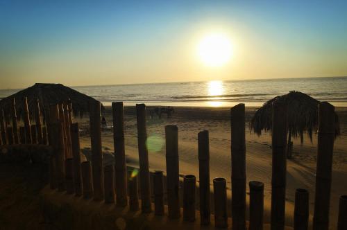 a beach with umbrellas and the ocean at sunset at Vichayito Bungalows & Carpas by Aranwa Hotels in Vichayito