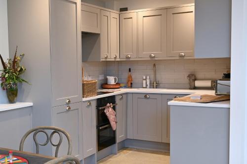 a kitchen with gray cabinets and white appliances at Oystercatcher - Converted luxury steading in Perth