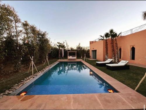 a swimming pool in a yard next to a house at Villa aquaparc piscine chauffée sans vis à vis in Marrakech