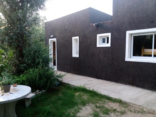 una casa negra con una ventana blanca y una mesa en Villa- Alba en Carpintería