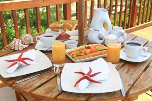 a wooden table with plates of food and cups of coffee at Vichayito Bungalows & Carpas by Aranwa Hotels in Vichayito
