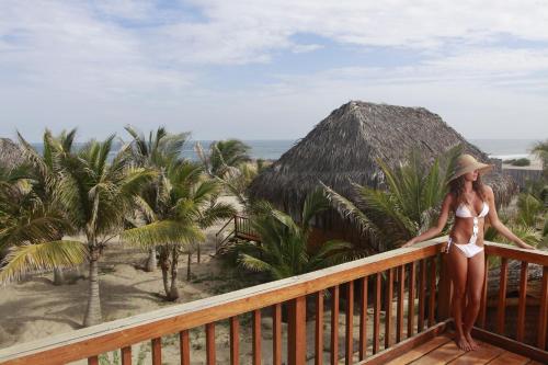 a woman in a bikini standing on a balcony at Vichayito Bungalows & Carpas by Aranwa Hotels in Vichayito