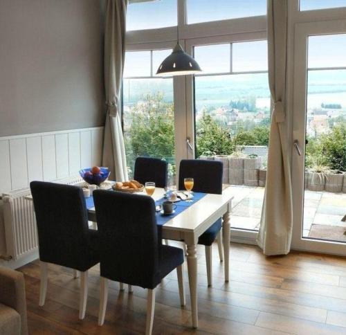 comedor con mesa y sillas y ventana grande en Modern ausgestattetes Ferienhaus mit möblierter Südhang-Terrasse im Altenautal, en Husen