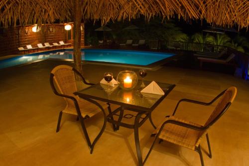 a table with a candle and two chairs in front of a pool at Vichayito Bungalows & Carpas by Aranwa Hotels in Vichayito
