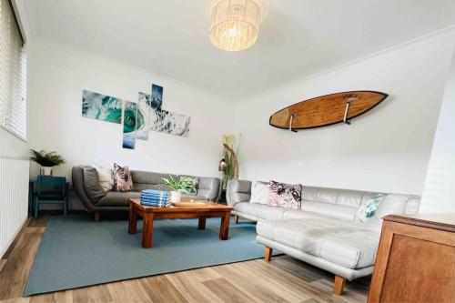 a living room with a couch and a surfboard on the wall at Palms34 5 minute walk to beach Bungalow in Westward Ho