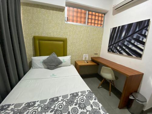 a small bedroom with a bed and a desk at Hotel Suites Regina in Veracruz