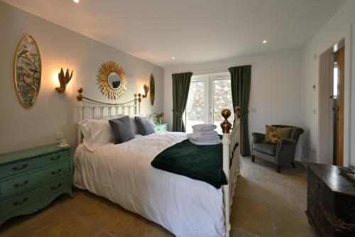 een slaapkamer met een bed, een stoel en een spiegel bij Capercaillie Cottage - Luxury converted steading in Perth