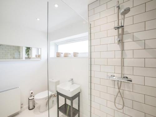 a white bathroom with a shower and a sink at Shore Lodge in Stornoway