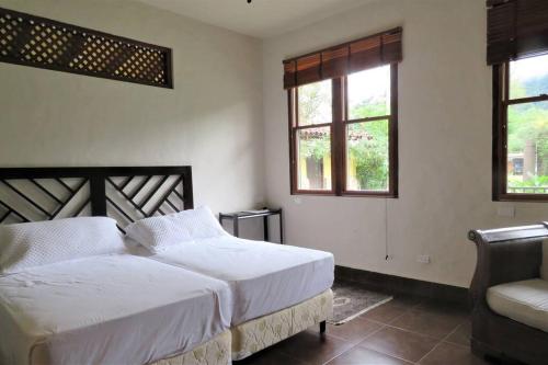 a bedroom with two beds and a chair and two windows at Vista Gaital/ Gaital View in Antón