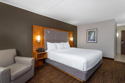 ein Hotelzimmer mit einem Bett und einem Stuhl in der Unterkunft Ramada by Wyndham Northern Grand Hotel & Conference Centre in Fort Saint John