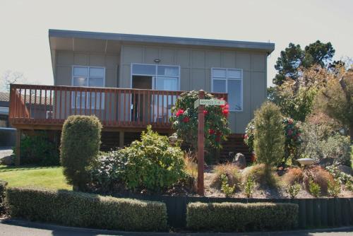 a house with a deck with flowers and bushes at Taupo Debretts Spa Resort in Taupo