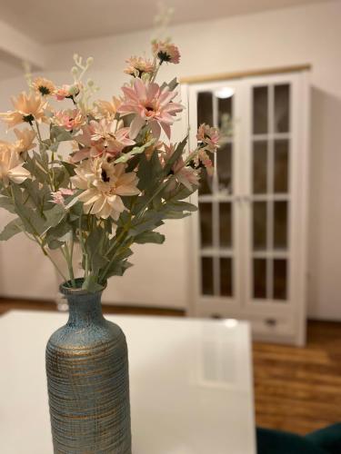 a vase filled with pink flowers on a table at Apartment Medjugorje Magnificat DeLuxe in Međugorje
