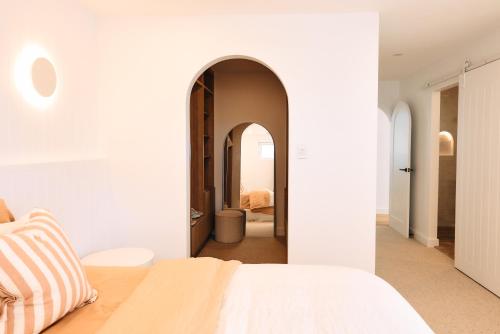 a bedroom with a white bed and an archway at Entre Palmas Ballina in Ballina