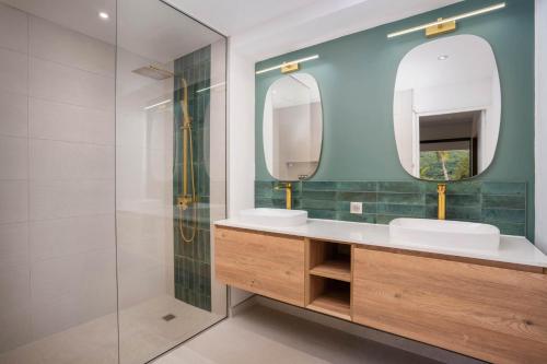 baño con 2 lavabos y ducha de cristal en Cook's Bay Hotel & Suites en Paopao