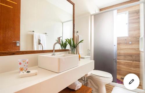 a bathroom with a sink and a toilet and a mirror at Geribá Apart Hotel Internacional Buzios in Búzios