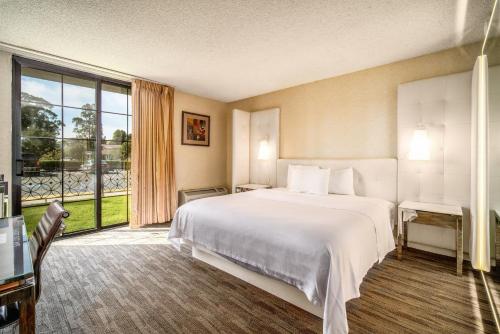 Cette chambre comprend un lit et une grande fenêtre. dans l'établissement Hotel Calle Joaquin - San Luis Obispo, à San Luis Obispo