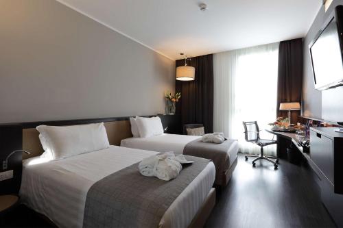 una camera d'albergo con due letti e una televisione di Best Western Premier CHC Airport a Genova