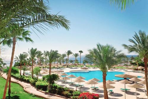 vistas a una piscina del complejo con sombrillas y palmeras en Domina coral bay Sultan - private room, en Sharm El Sheikh