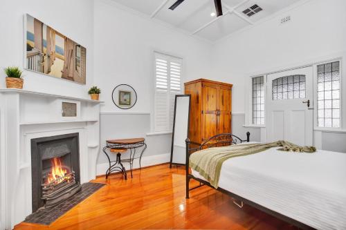 a bedroom with a bed and a fireplace at Noir Cottage Glenelg North in Glenelg