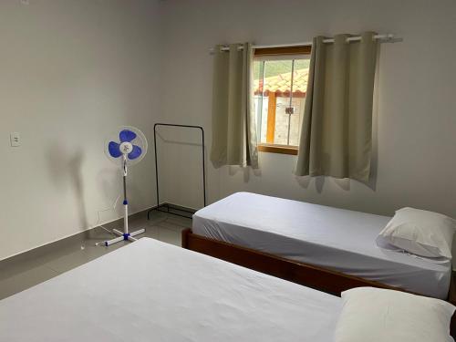 a room with two beds and a fan and a window at Casa Ametista in Pirenópolis