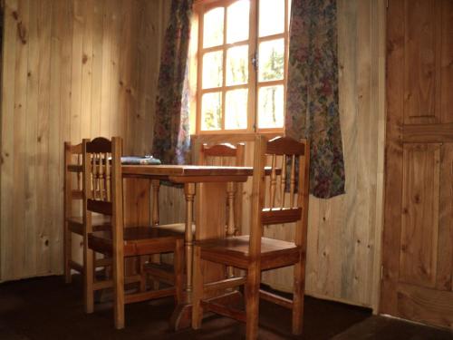 a wooden table and chairs in a room with a window at Cabaña Rustica Patagonia Chilena in Coñaripe