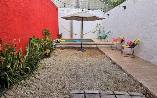 a patio with an umbrella and chairs and a pool at La 78 alberca y garage con porton electrico in Mérida