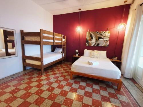 a bedroom with two bunk beds and a red wall at La 78 alberca y garage con porton electrico in Mérida