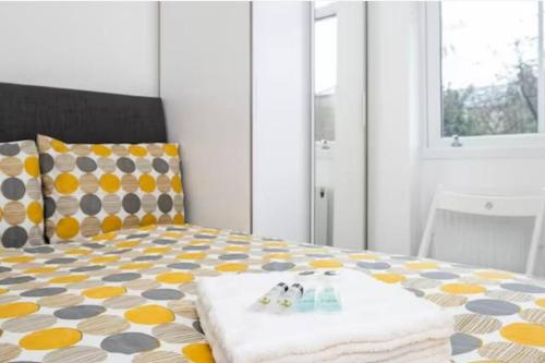 - une chambre avec un lit aux motifs jaune et gris dans l'établissement Great Location Service and Stay Double Ensuite Room - 5mins Walk From Tufnell Park, à Londres