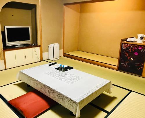 a living room with a table and a tv at Hotel Clio Court Hakata in Fukuoka