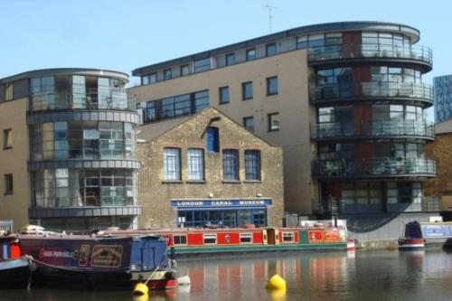 a boat in the water in front of some buildings at Victorian Building turned Charming Hotel Perfect For Short and Long Term Stay with WiFi in London