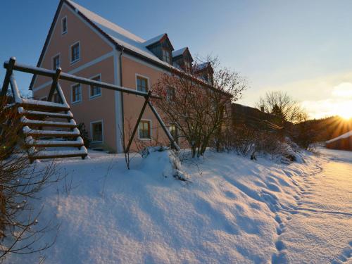 a house in the snow with a staircase in front at Ferienhaus mit Wellnessbereich in Schönsee