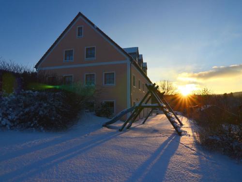 a house with the sun setting next to a building at Ferienhaus mit Wellnessbereich in Schönsee
