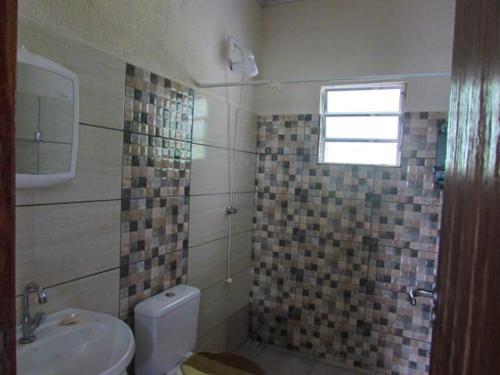 a bathroom with a toilet and a sink and a window at Chácara Rio Cachoeira in Antonina