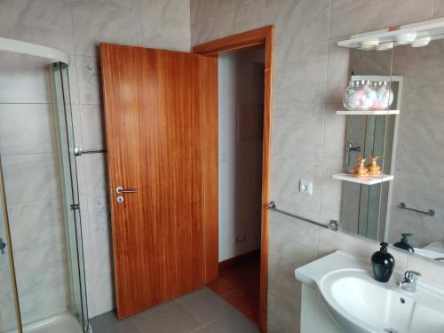 uma casa de banho com um chuveiro, um lavatório e uma porta de madeira em Casa da Eira em Calheta