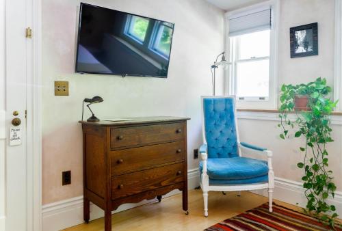 a room with a dresser and a blue chair and a tv at Argos Inn - Ithaca's Boutique Hotel in Ithaca