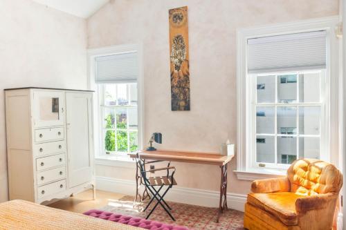 a bedroom with a desk and a chair and windows at Argos Inn - Ithaca's Boutique Hotel in Ithaca
