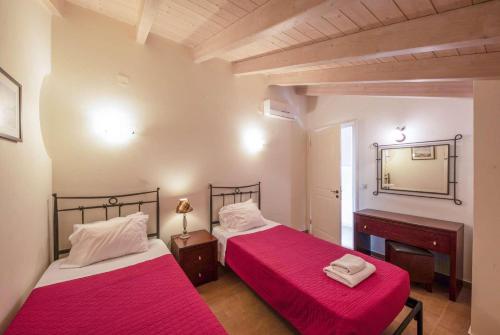 Almiros BeachにあるGialettiの赤いシーツと鏡が備わる客室のベッド2台