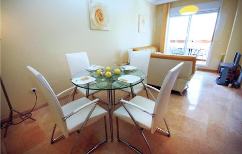 a dining room with a glass table and white chairs at Nice Apartment In Benalmádena Costa in Benalmádena