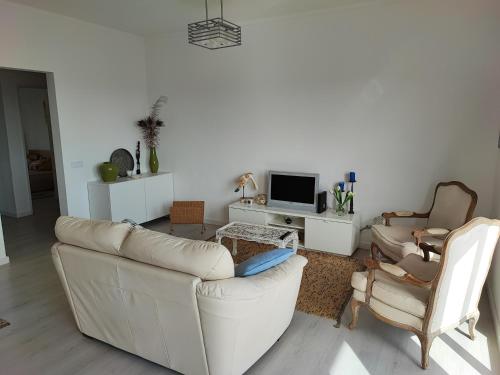 een woonkamer met een witte bank en 2 stoelen bij Milu house in Faro