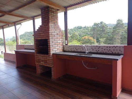 een keuken met een wastafel en een bakstenen oven bij Chácara Biritiba Mirim, Bairro Nirvana - Mogi das Cruzes in Biritiba-Mirim
