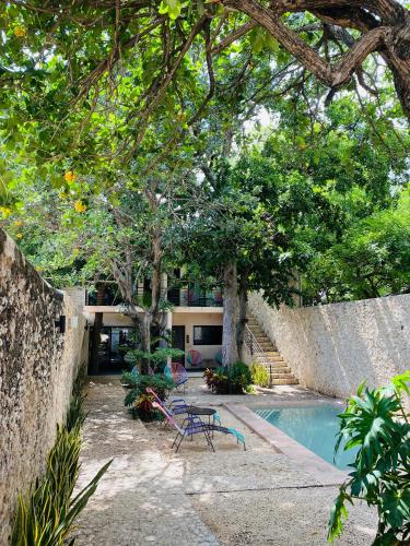 a swimming pool with a table and chairs next to a building at Hotelito YUM KAAX in Mérida