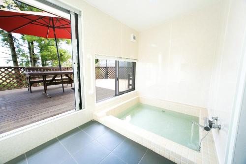 eine Badewanne in einem Zimmer mit Sonnenschirm in der Unterkunft Y's あたみんち in Atami