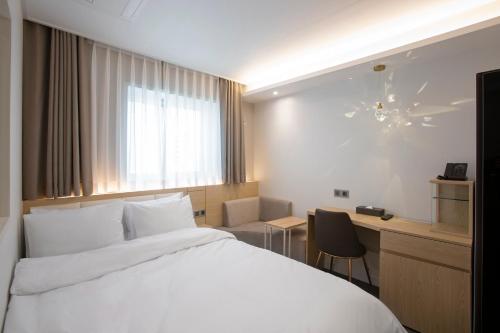 a hotel room with a white bed and a desk at Busan Lounge 26 Hotel in Busan