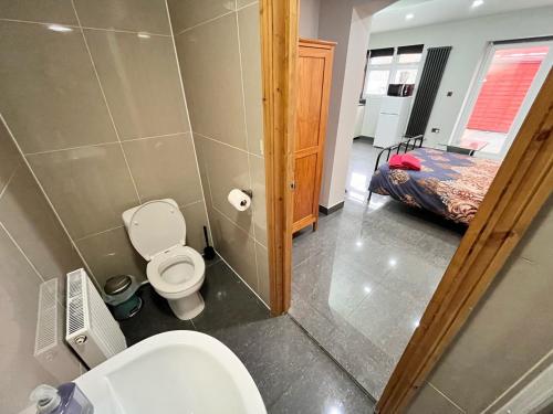 a bathroom with a toilet and a bed at Full Studio Near Heathrow Airport & London in Hayes