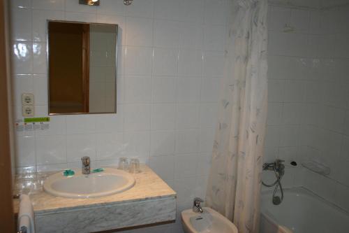 a bathroom with a sink and a tub and a mirror at Hotel Llacs De Cardos in Tavascan
