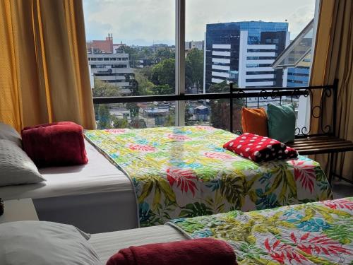 two beds in a room with a large window at Lindo Apartamento 1102 zona 9 in Guatemala