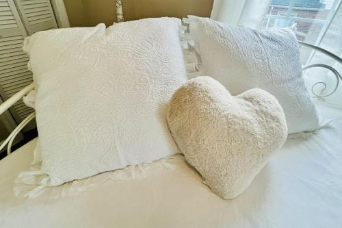 a heart pillow sitting on a bed with pillows at Coastal Casita by the River in New Bern