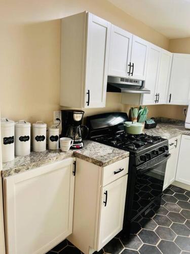 a kitchen with white cabinets and a stove top oven at Coastal Casita by the River in New Bern