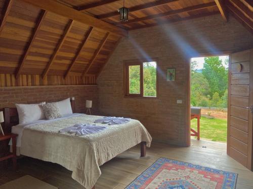 um quarto com uma cama num quarto com uma janela em Pousada Recanto do Sauá - Monte Verde em Monte Verde
